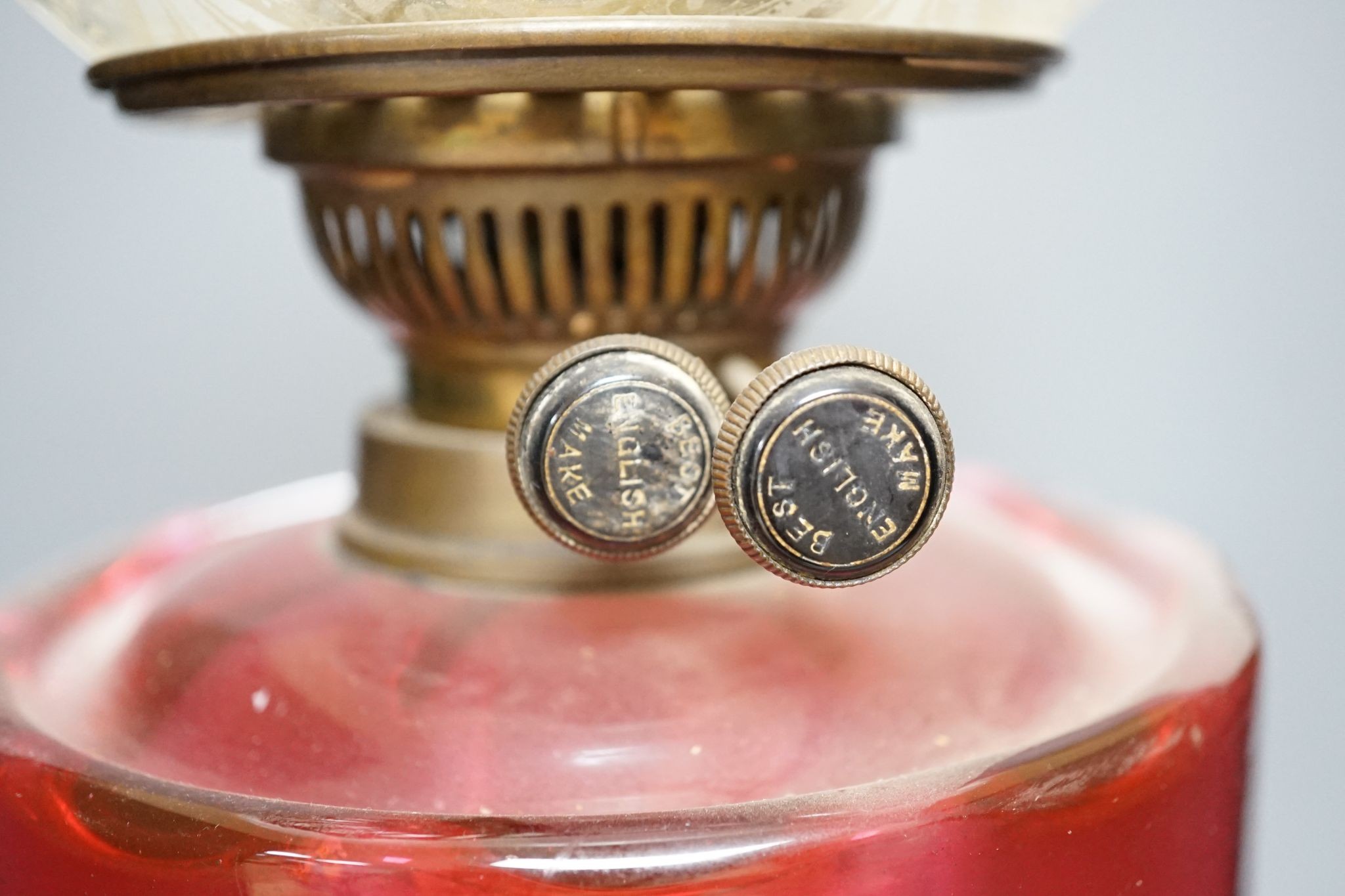 A brass and cranberry glass oil lamp with shade and chimney, total height 66cm